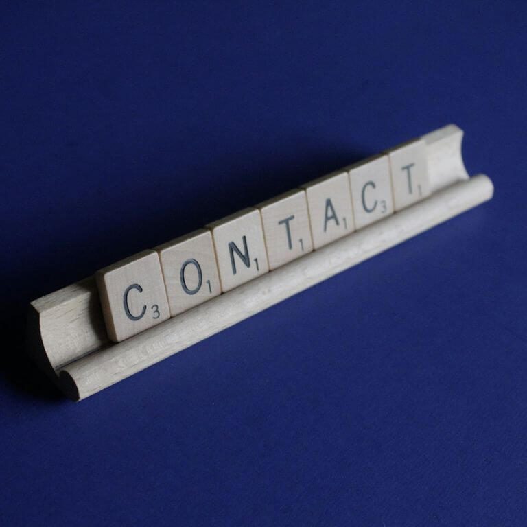 Ein Schild mit dem Wort "CONTACT" auf einer blauen Oberfläche.